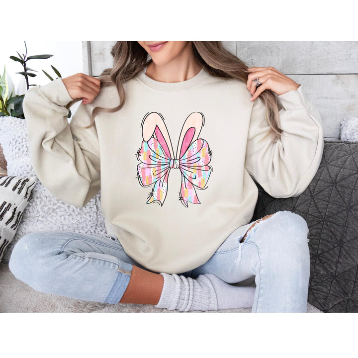 A stylish DTF transfer with hand-drawn bunny ears and a large watercolor bow in pink, blue, and yellow.