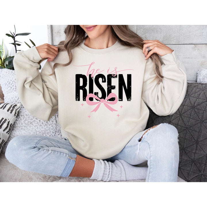 Inspirational Easter transfer with "He Is Risen" in large black lettering, pink bow, and star accents.