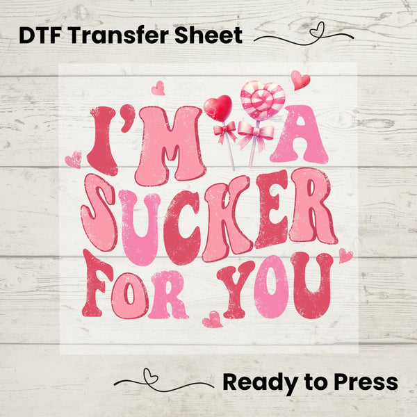 A graphic design of text 'I'M A SUCKER FOR YOU' in various shades of pink, presented on a white background, indicating a Valentine's themed DTF transfer sheet.