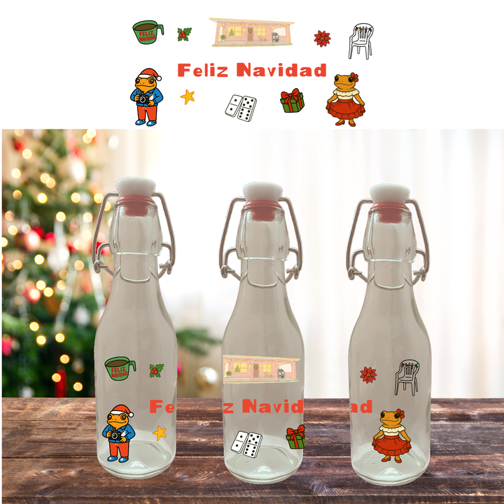 Three glass bottles with festive stickers and 'Feliz Navidad' text on a wooden surface with a blurred Christmas tree in the background.