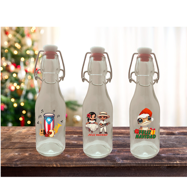 Three glass bottles with festive designs on a wooden surface with a Christmas tree in the background.