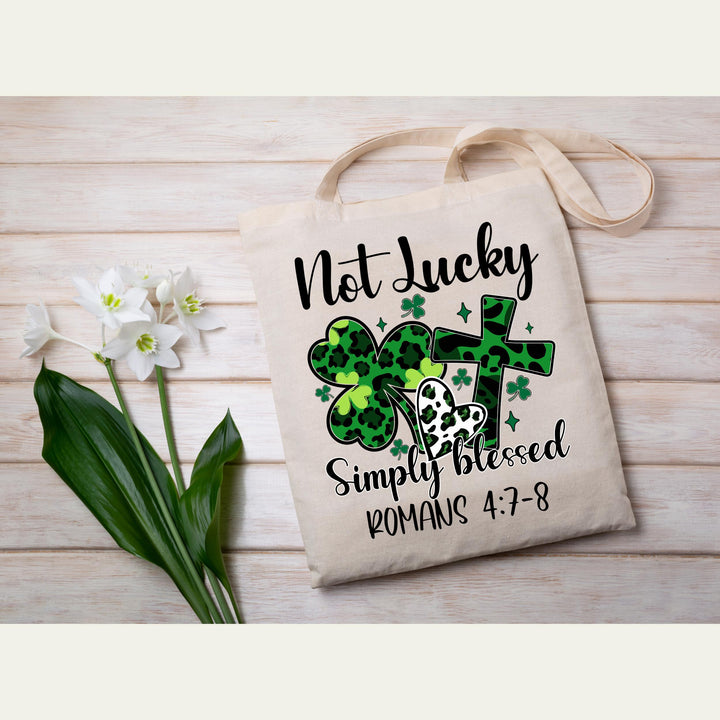 Not Lucky Simply Blessed DTF transfer featuring green leopard shamrocks, hearts, cross, and inspirational Romans 4:7-8 scripture—perfect for DIY faith apparel.